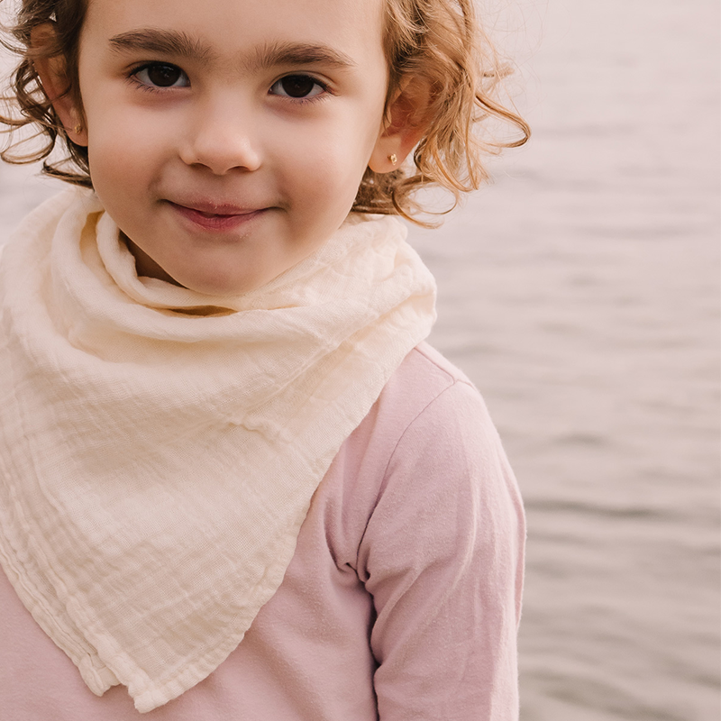 Mädchen ist am See und trägt Nuschi aus Musselin in Beige von Petit Stellou um den Hals. 