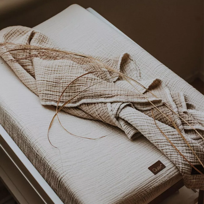 Decke aus Musselin in Beige für Babys von Quax liegt auf Wickelkissen