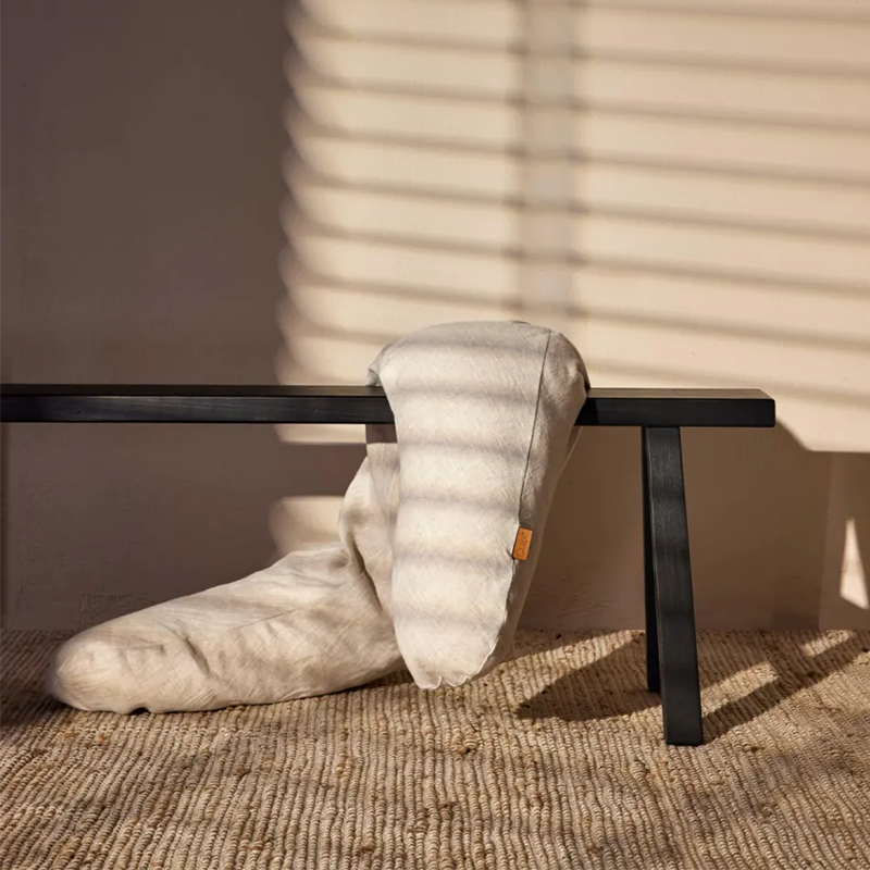 Stillkissen aus Leinen in Beige von Quax auf einer schwarzen Bank.