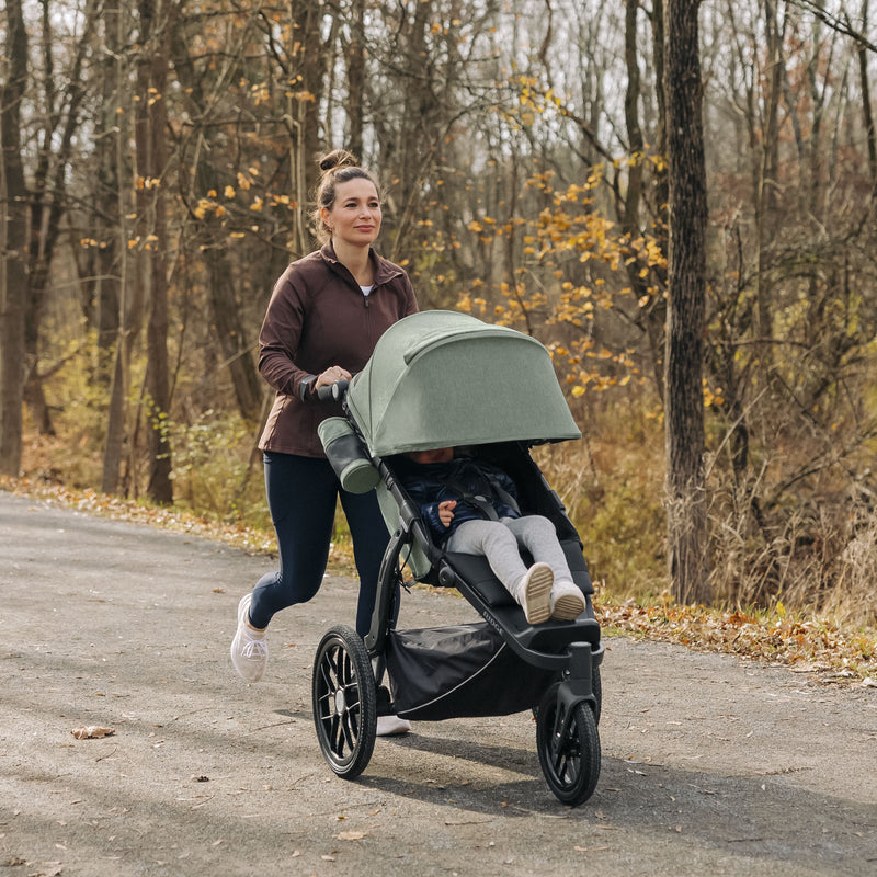 Mutter joggt durch den Wald mit Kind im Uppababy Ridge Gwen 