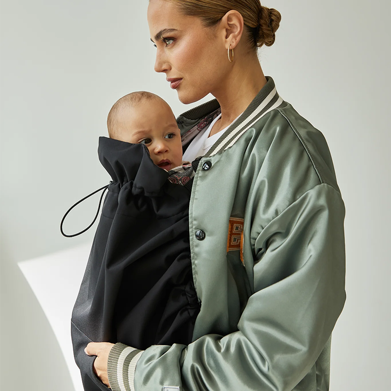 Sandiia Alwetter-Cover für Babytrage in Schwarz mit Vordertaschen für den Träger. Nahaufnahme von der Seite.