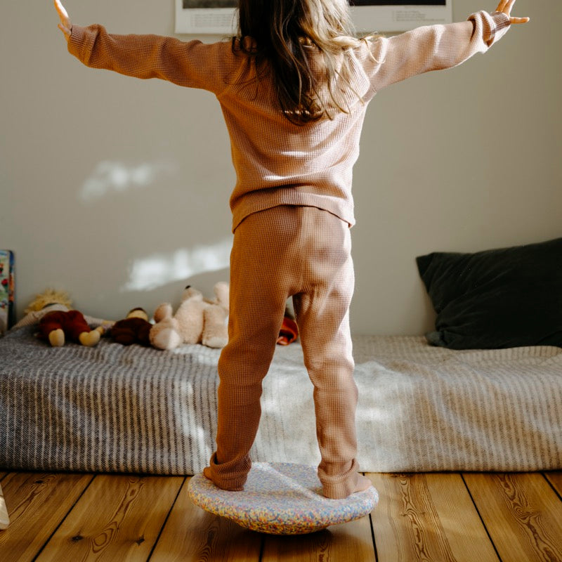Kind balanciert auf dem Confetti Pastel Board von Stapelstein