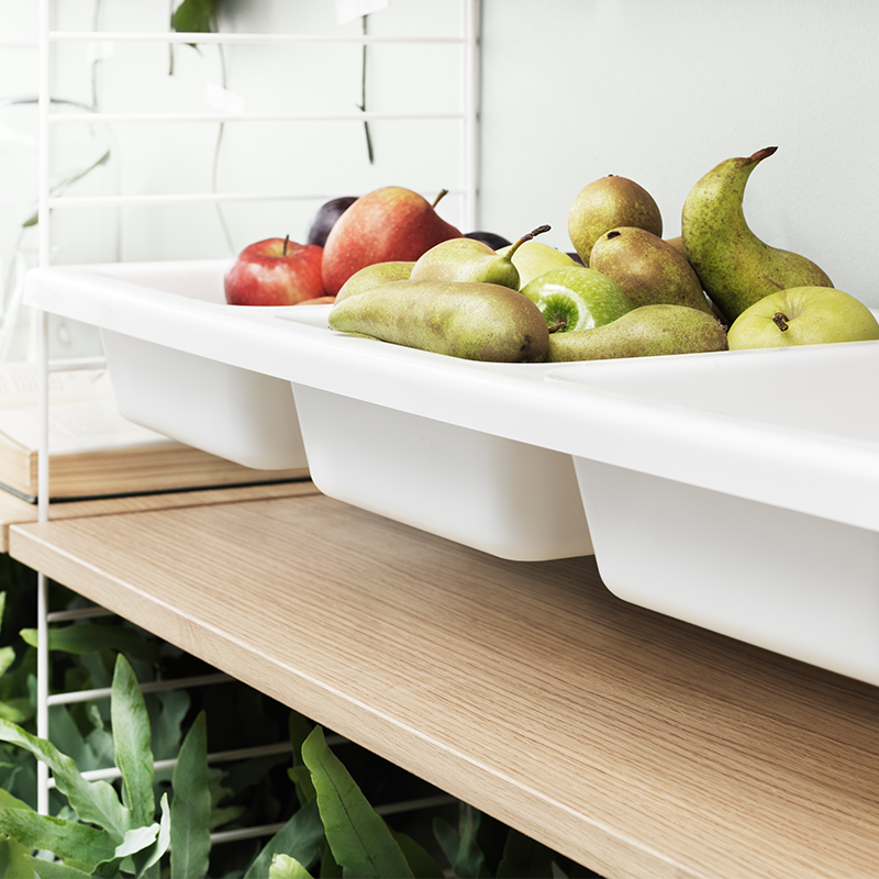 Aufbewahrungseinsatz mit drei einzelnen Einsätzen in Weiss gefüllt mit Äpfeln und Birnen und eingesetzt in einem String Furniture Regal. 