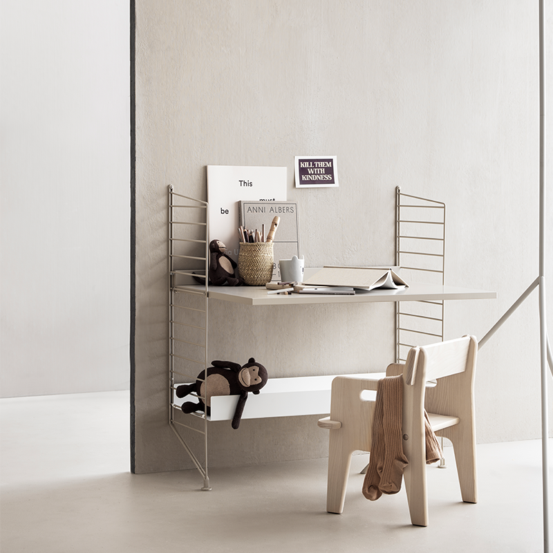 String Furniture Regal in Beige mit Tischplatte in Beige und Bodenregal mit hohen Kanten. Mit Kinderspielzeug und Kinderstuhl.