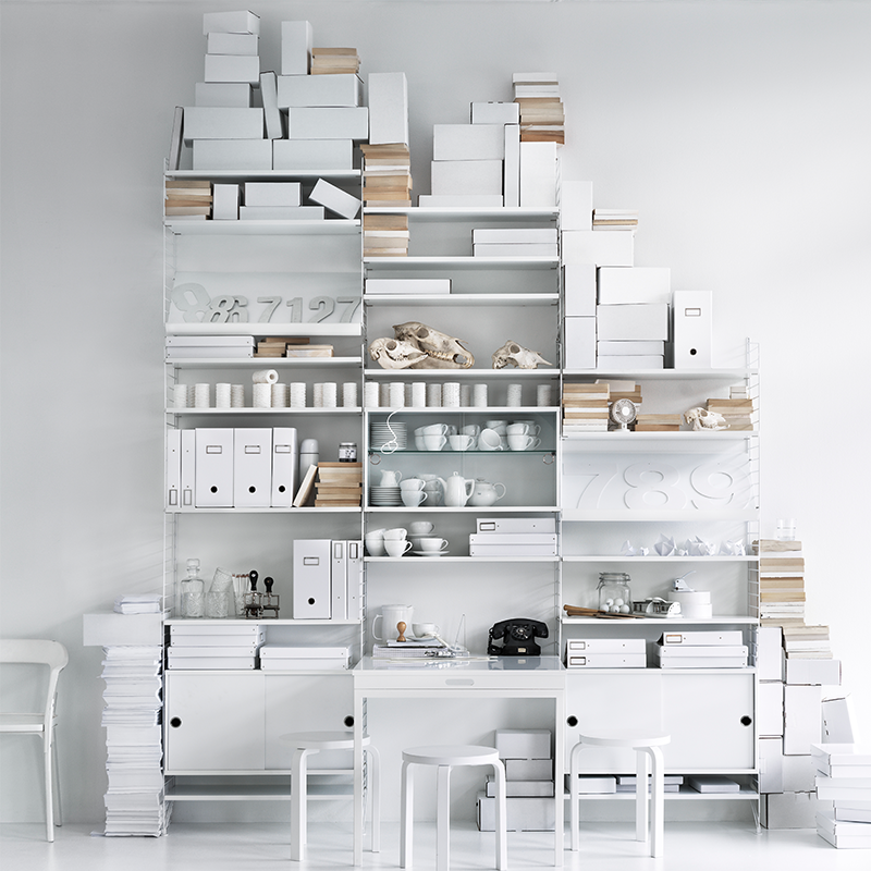 String Furniture Regalsystem in Weiss mit Regalböden in Weiss, Tischplatte in Weiss, Schrankelementen mit Schublade in Weiss. 