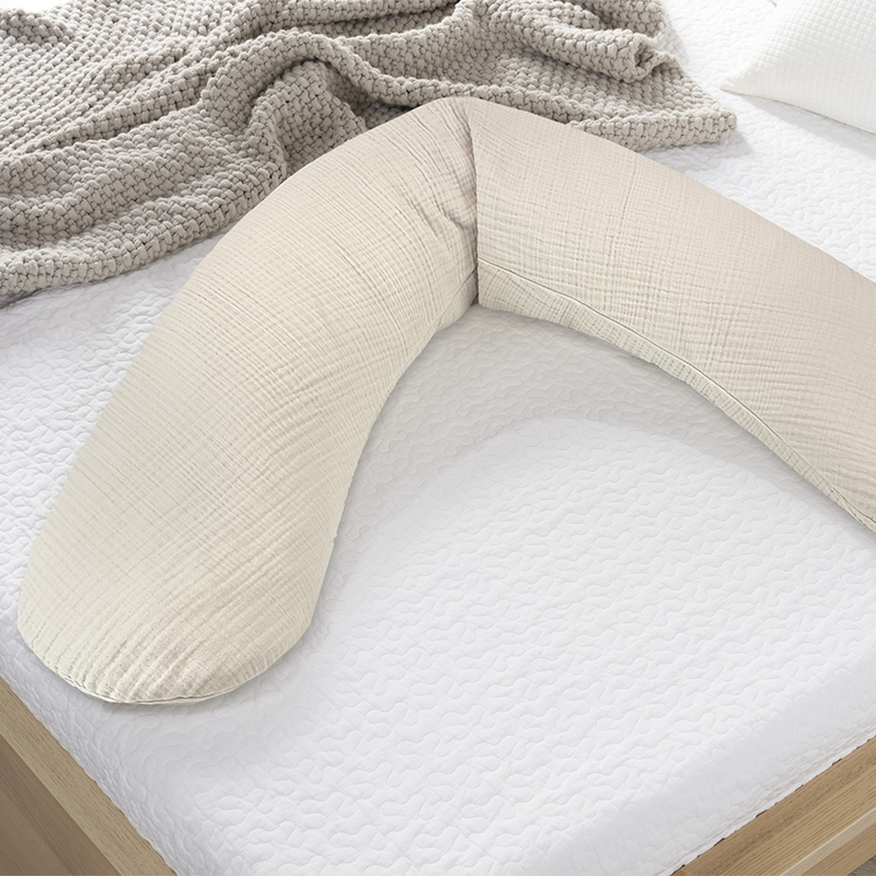 Still-und Schwangerschaftskissen in Beige liegt auf einem Bett.