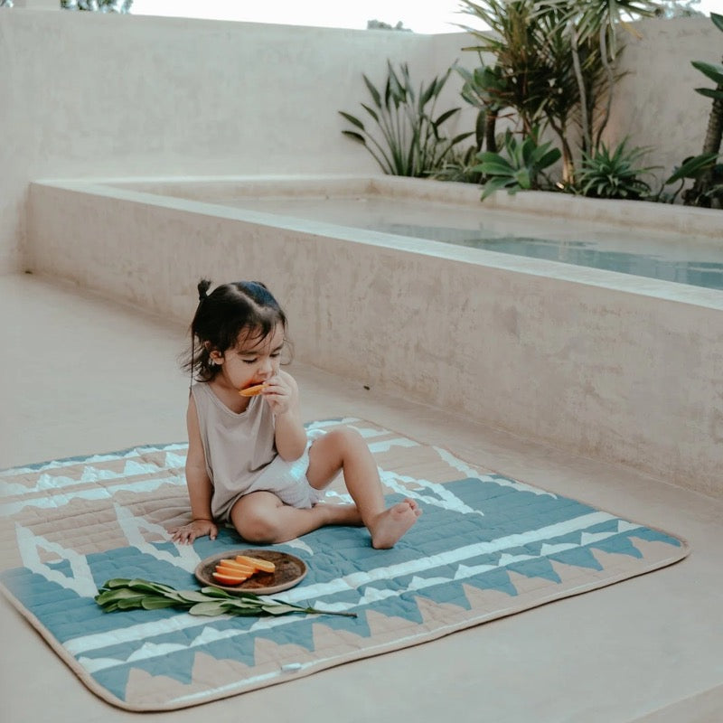 Ein Kind isst Früchte auf der rechteckigen Spielmatte von Toddlekind