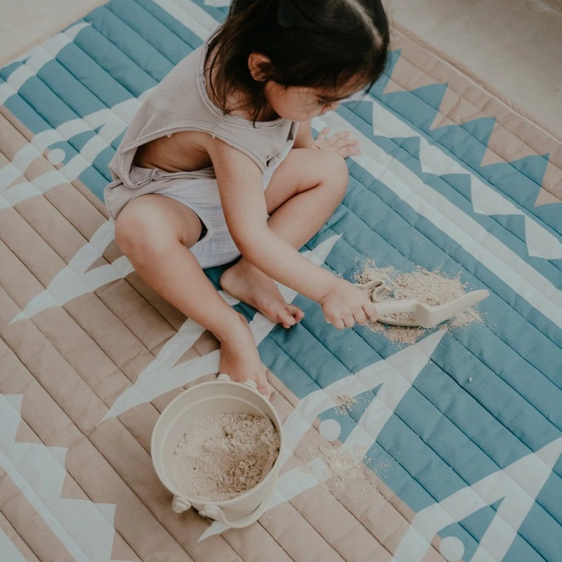 Kind spielt auf der wasserfesten Spielmatte von Toddlekind mit hübschem Muster in Beige und Hellblau
