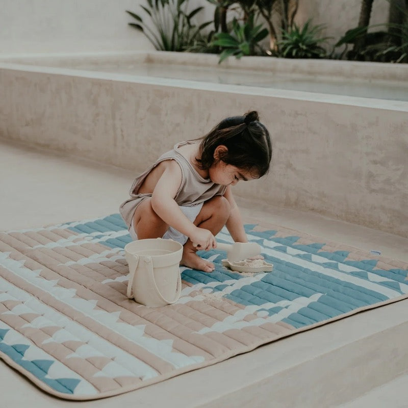 Kind spielt mit Sand auf der wasserfesten Spielmatte von Toddlekind im Design &quot;Mineral&quot;