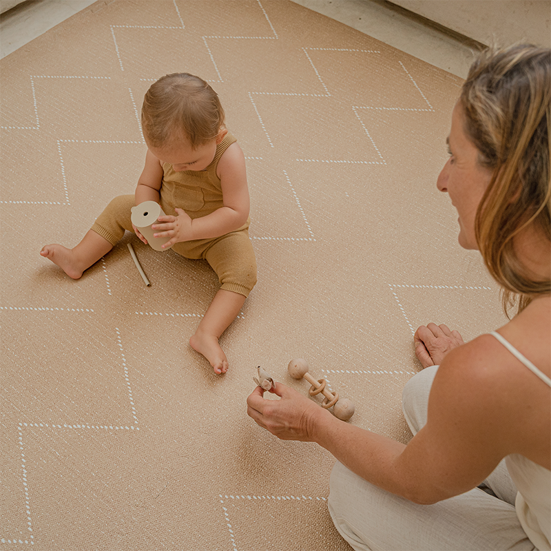 Baby spielt mit seiner Mama auf der Toddlekind Spielmatte Tulum in der Farbe Sandstone mit 6 einzelnen Puzzleteilen. 