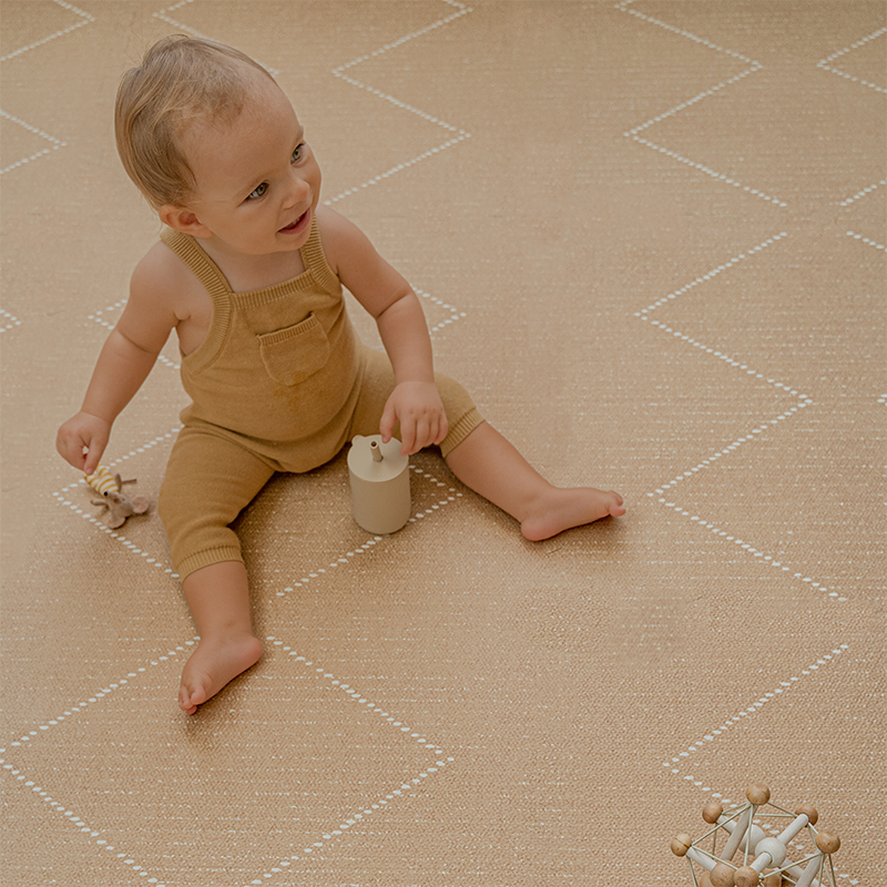 Kleinkind spielt auf der Toddlekind Spielmatte Tulum in der Farbe Sandstone mit 6 einzelnen Puzzleteilen. 