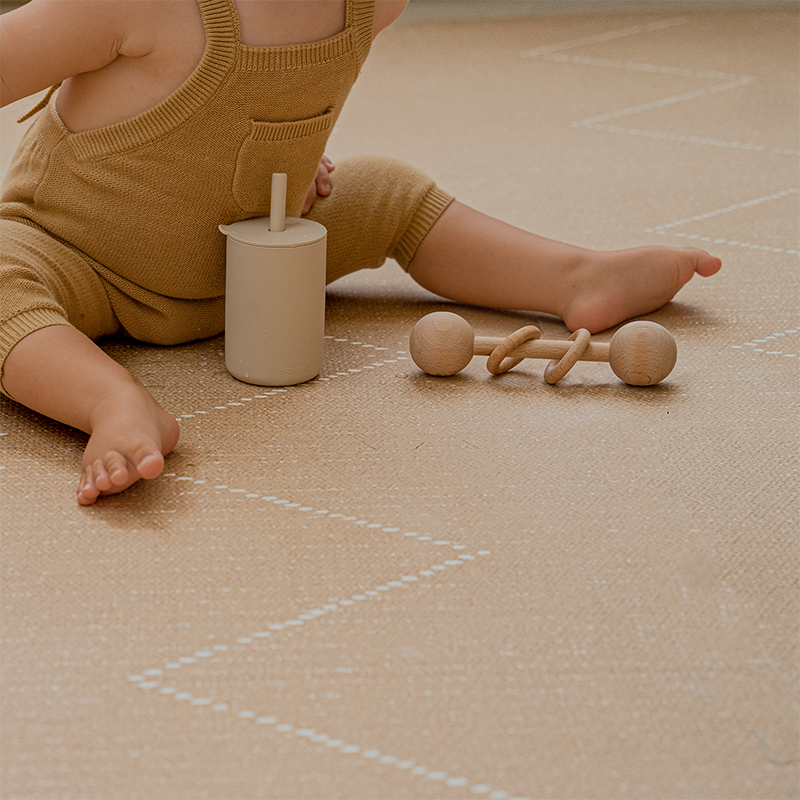 Toddlekind Spielmatte Tulum in der Farbe Sandstone mit 6 einzelnen Puzzleteilen. und Kind mit seinen Spielsachen.
