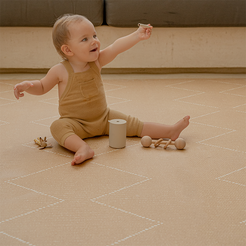 Kind spielt mit seinen Spielsachen auf der Toddlekind Spielmatte Tulum in der Farbe Sandstone mit 6 einzelnen Puzzleteilen. 