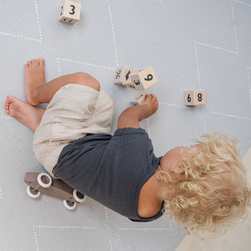 Bub spielt auf der Toddlekind Spielmatte Tulum in der Farbe Stone. 