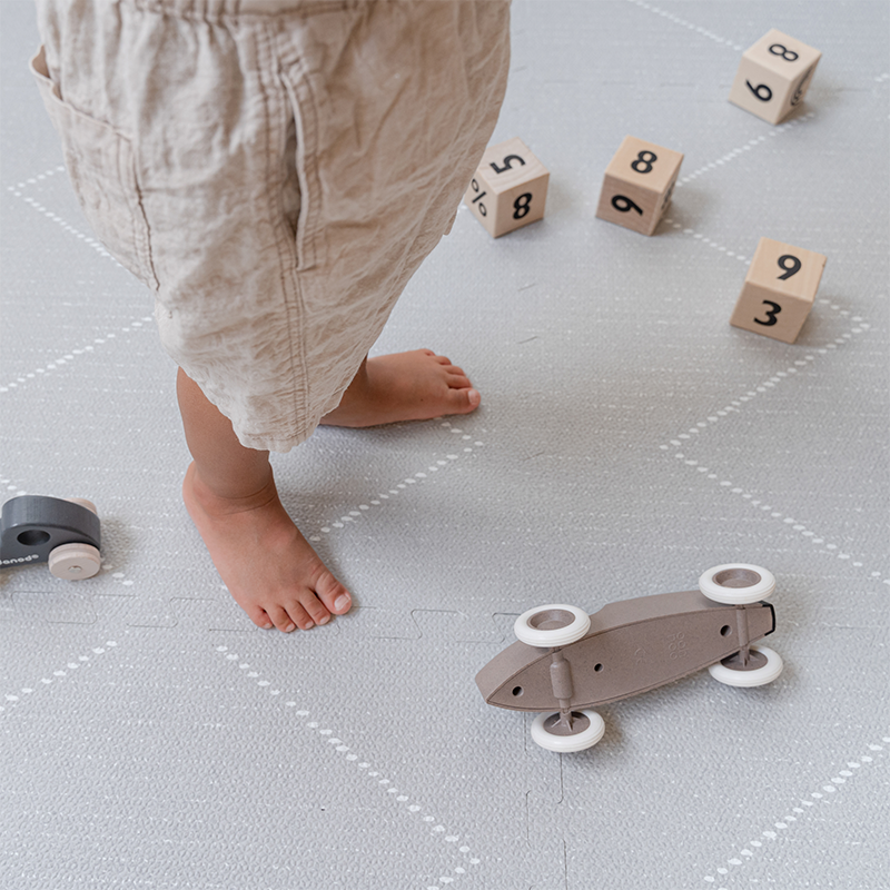 Spielsachen auf der Toddlekind Spielmatte Tulum in der Farbe Stone.