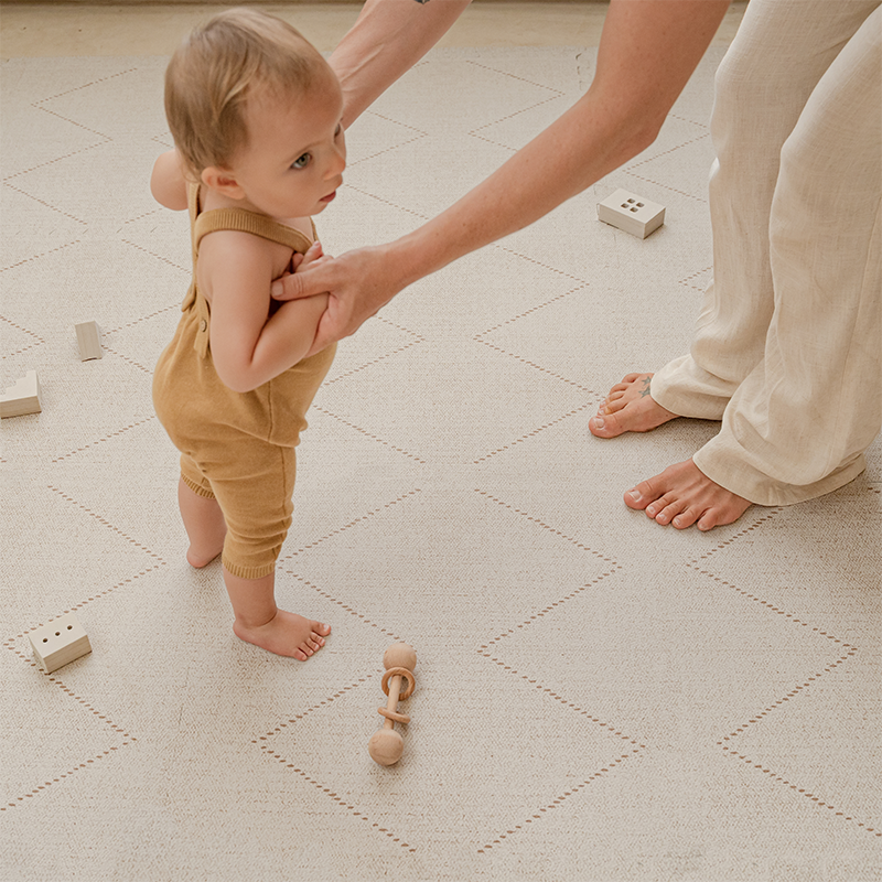 Mama und Baby spielen auf der Toddlekind Spielmatte Tulum in der Farbe Bone. 