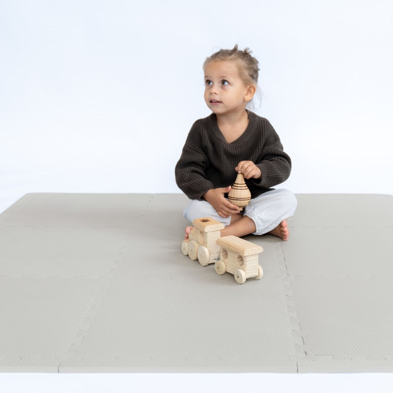 Kind sitzend auf der Classic Spielmatte in &quot;Stone&quot; Grau von Toddlekind