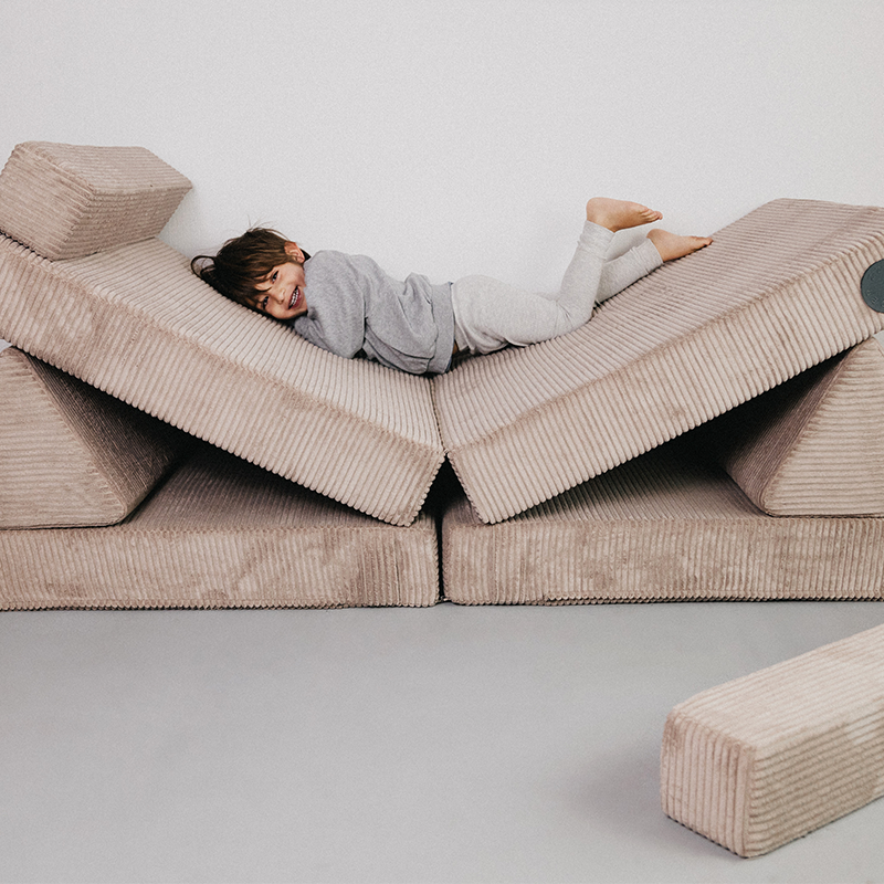 Kind spielt auf dem Wonderwuzz Spielsofa für Kinder in der Farbe Taupe.