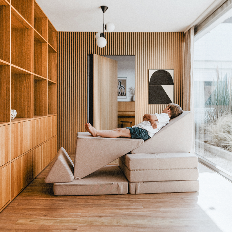 Junge der auf dem Wonderwuzz Spielsofa mit 8 modularen Teilen &#39;Oh so sofy&#39; in der Farbe Beigemarie liegt. 