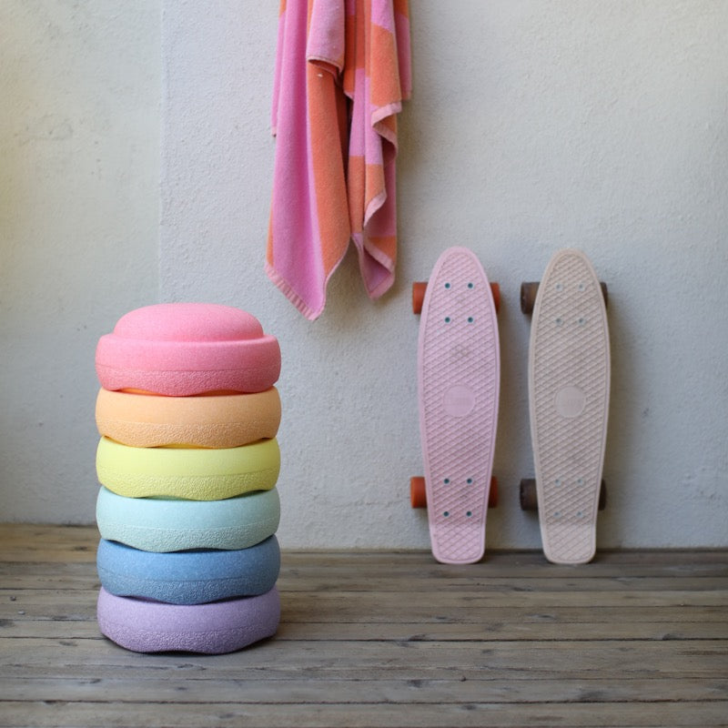 Set mit 6 Stapelsteinen in schönen Regenbogenfarben in Pastell neben zwei Skateboards